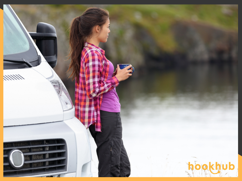 Woman with coffee mug next to camper van